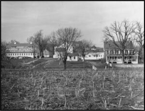Historic black and white photograph of the farm property showing the barn, farmhouse, and other support structures.