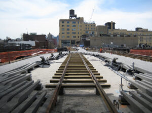 A photograph of ongoing construction of the High Line, showing some of the concrete paving slabs in place and the railway in through the middle.