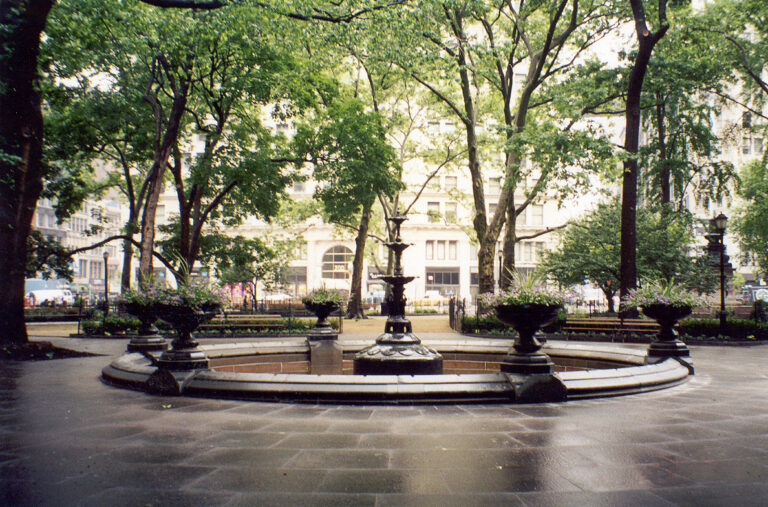 Photograph of the fountain at the park; the fountain is off and drained.