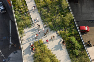 A direct overhead image of the High Line above a "Y"-shaped path with several people strolling and a few sitting on benches.
